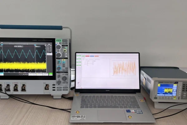 TDR Impedance Measurement Laboratory electronics setup: an oscilloscope showing a waveform on the left, a laptop with data graphs in the center, and a signal instrument on the right on a desk.