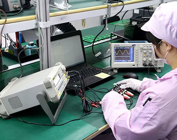 industrial-pcb-review-assembly Operator using an oscilloscope and test equipment at an electronics workbench