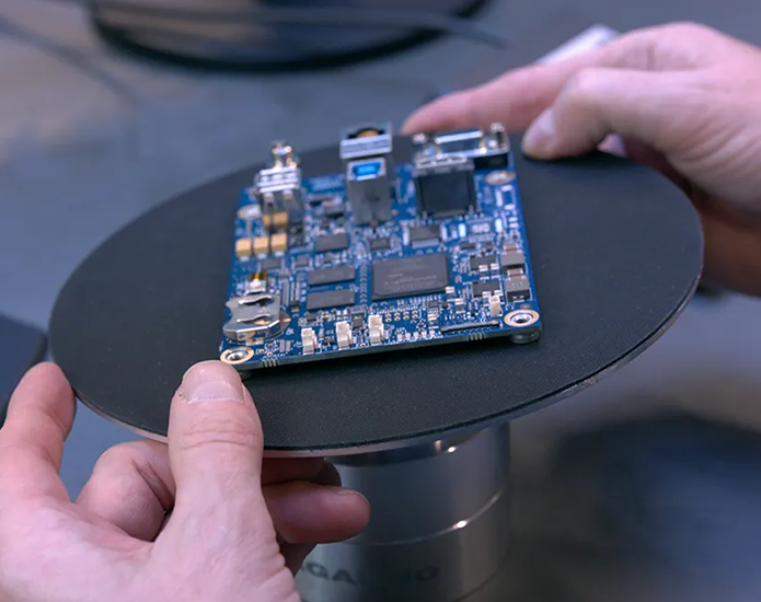 industrial-pcb-review-environment Populated circuit board held over a circular inspection fixture
