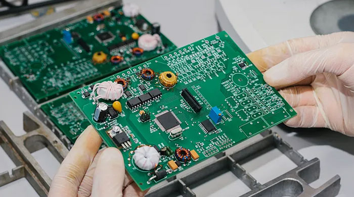 Gloved hands holding a populated circuit board