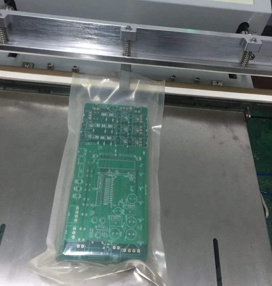 Bare printed circuit boards in a clear protective bag beneath a sealing machine