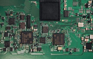 Populated green circuit board with integrated circuits, surface-mount components and visible routed traces