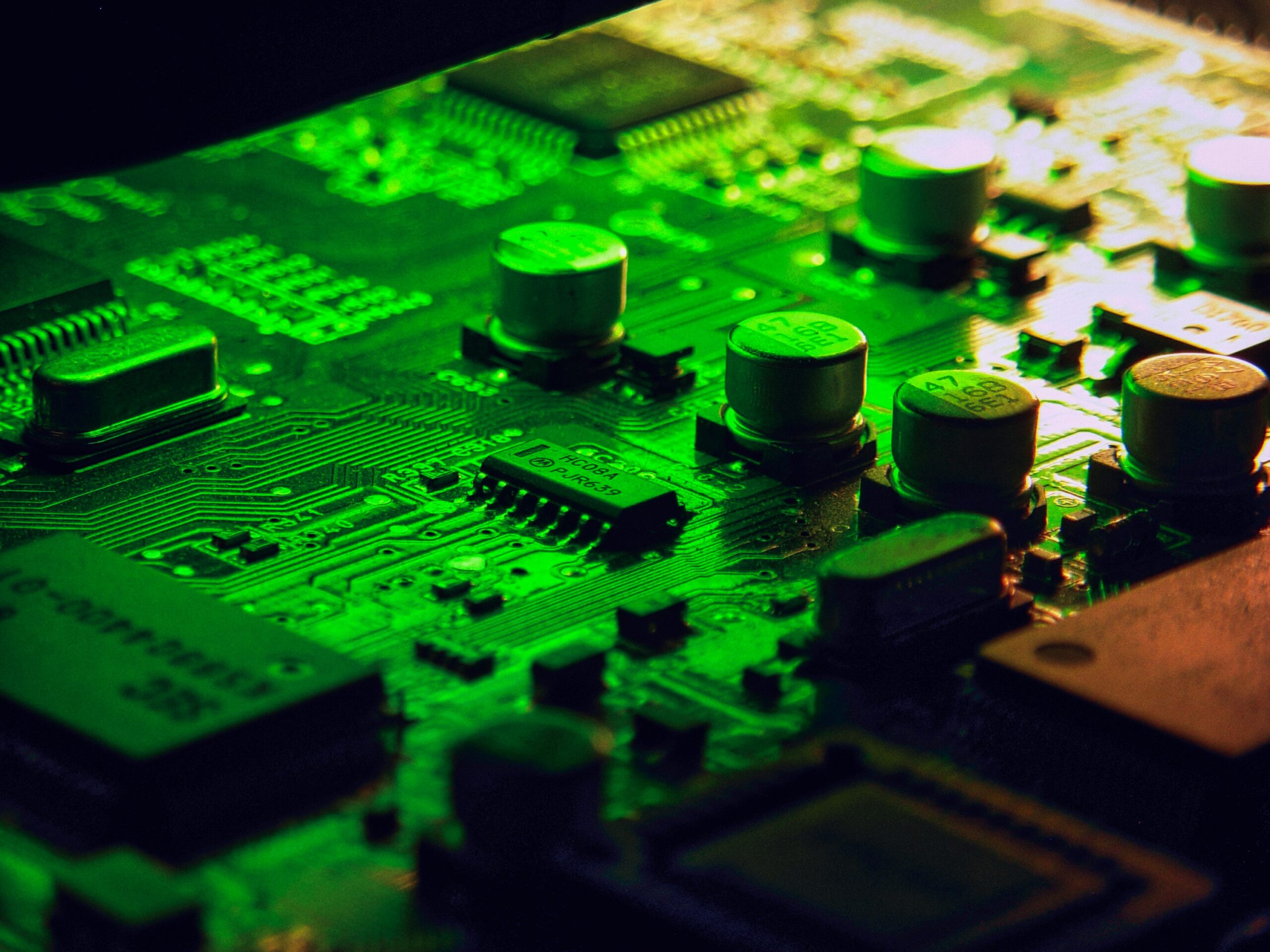 Close-up of a populated green circuit board with visible traces, capacitors and integrated circuits